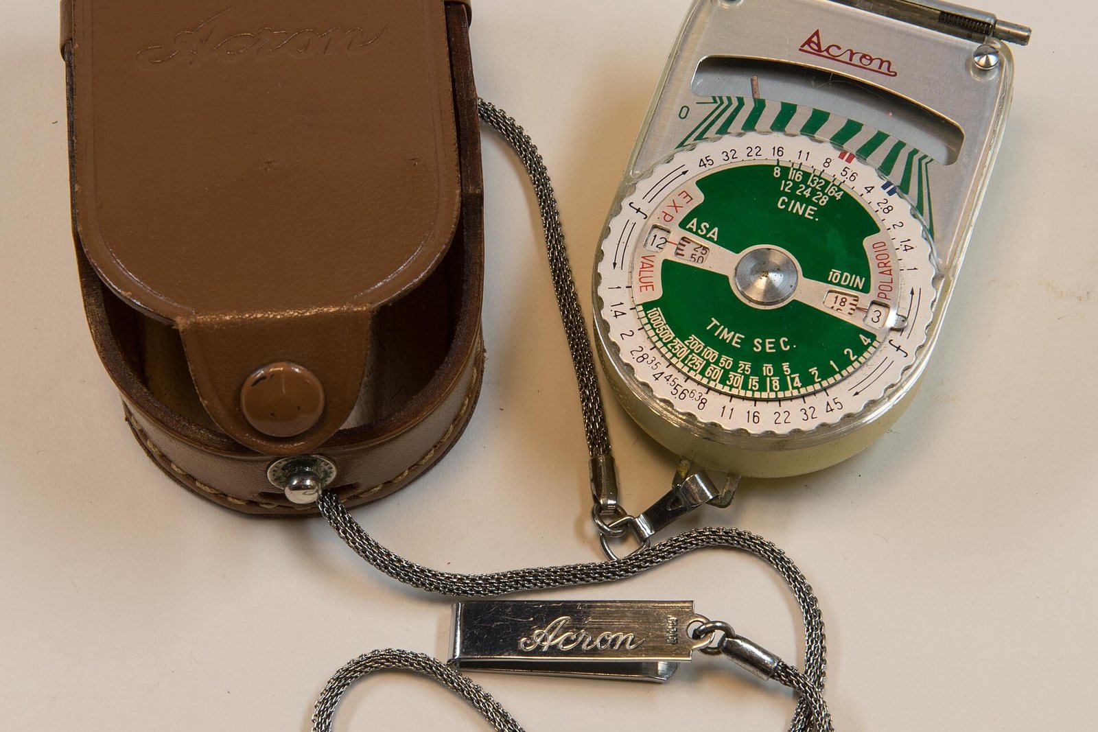 An old handheld light meter with its leather case.